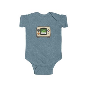 May include: A blue baby bodysuit featuring a retro handheld video game graphic. The game console is beige with a green screen displaying a pixelated landscape. It has orange and purple buttons. A fun and nostalgic design for a baby.