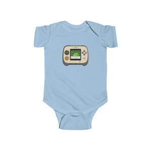 May include: Light blue baby bodysuit featuring a retro handheld video game graphic. The game console is beige with a green screen displaying a pixelated landscape. It has orange and colorful buttons. A fun and nostalgic design for infants.