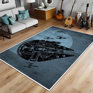 May include: A rectangular rug with a black spaceship design on a blue background, with a light blue circle. The rug is placed on a wooden floor.