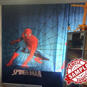 Op de afbeelding: Blauw Spider-Man gordijn met een groot beeld van de superheld in een dynamische pose. Het gordijn heeft een spinnenwebpatroon op de achtergrond en de woorden "Spider-Man" onderaan.