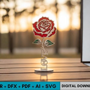 May include: A wooden rose sculpture with a red and white flower, green leaves, and the word "LOVE" at the base. The rose is on a round base. The background is blurred with warm tones.