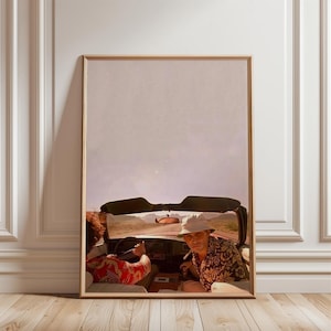 May include: Framed print depicting two people in a convertible car on a desert road. The driver wears a floral shirt, sunglasses, and a hat. The passenger wears a red patterned shirt. The background shows a desert landscape.