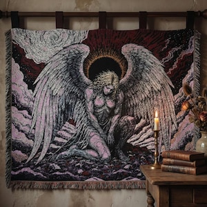 May include: A tapestry depicting a kneeling angel with large wings, set against a backdrop of clouds and a dark red sky. The angel is rendered in shades of pink, gray, and black, with a golden halo. The tapestry is hung on a wooden rod.