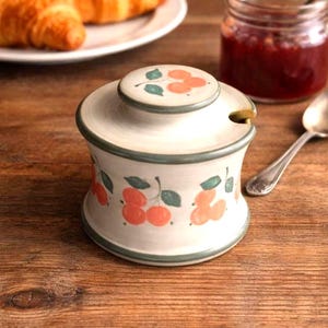 May include: A white ceramic mug with a black handle and the text "But First, Coffee" in a handwritten style. The mug is on a white surface. The mug is approximately 4 inches tall.