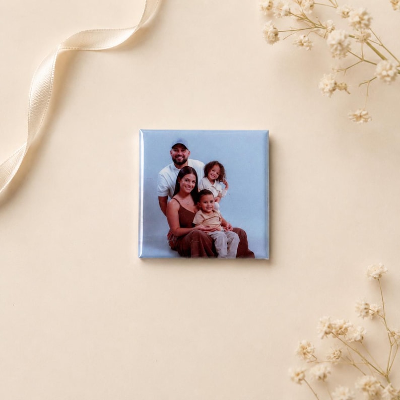 K&ouml;nnte beinhalten: Ein quadratischer Magnet mit einem aufgedruckten Foto einer vierk&ouml;pfigen Familie. Das Bild zeigt einen Mann, eine Frau und zwei Kinder, die gemeinsam vor einem hellblauen Hintergrund posieren. Der Magnet hat eine gl&auml;nzende Oberfl&auml;che.