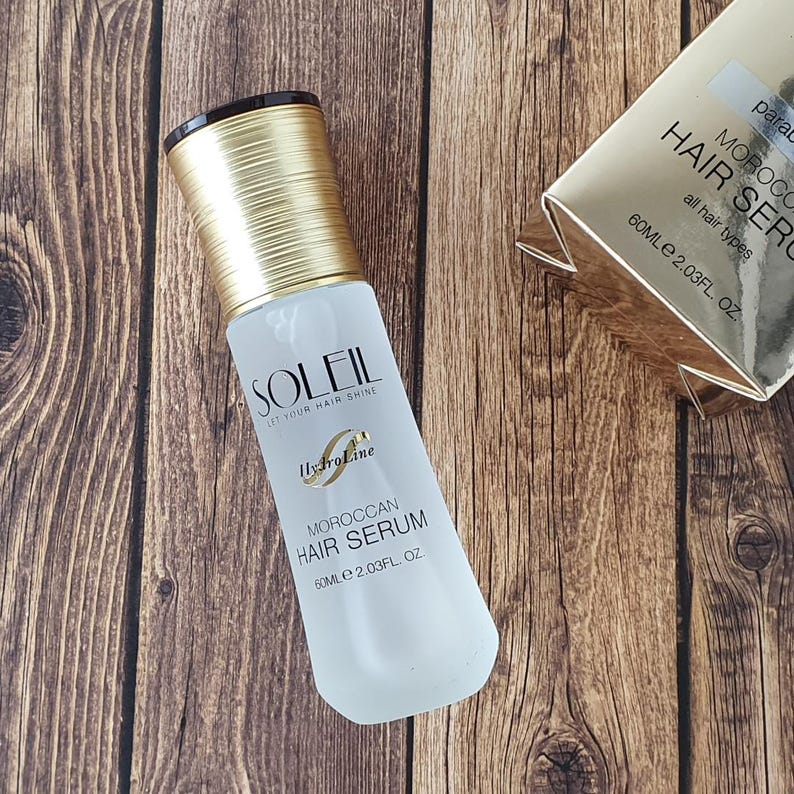 May include: A white bottle of Soleil Moroccan Hair Serum with a gold cap and the text "SOLEIL LET YOUR HAIR SHINE". The bottle contains 60ml (2.03 fl oz) of serum and is for all hair types.