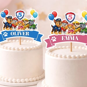 May include: Two white frosted cakes with decorative borders. Each cake has a Paw Patrol themed topper with the name "Oliver" and "Emma" on banners. The toppers feature cartoon characters, balloons, and the number 5.