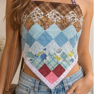 May include: A patchwork halter top with a variety of patterned fabrics in shades of blue, brown, and pink. The top is paired with light wash denim jeans. The halter straps are a purple and white gingham pattern.