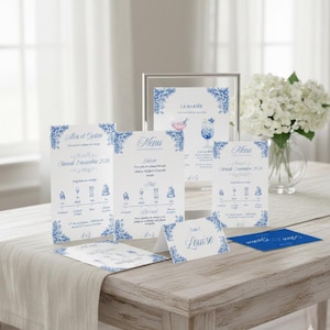 Peut inclure: Ensemble de papeterie de mariage élégante avec un motif floral bleu. L'ensemble comprend des invitations, des menus et des marque-places, tous avec des éléments décoratifs et du texte assortis. Un panneau encadré et une carte bleue sont également présents.