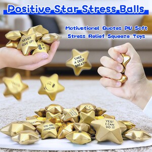 May include: Gold star-shaped stress balls with motivational quotes. The image shows several stars with phrases like "Never Give Up!" and "Yes! I Can Do It." Some stars have smiley faces. The text "Positive Star Stress Balls" is at the top.