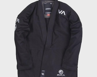 May include: Black martial arts gi with white logos. The gi features the letters "VA" on the shoulders and a circular logo with "RVCA" printed on the front. The gi has a collar and is designed for martial arts training.