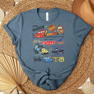 Puede incluir: Camiseta azul con personajes de dibujos animados de la pel&iacute;cula Cars, incluyendo a Rayo McQueen, Mate y Sally. El dise&ntilde;o incluye el texto "Lightning McQueen" y "Cars". La camiseta est&aacute; hecha de un material suave.
