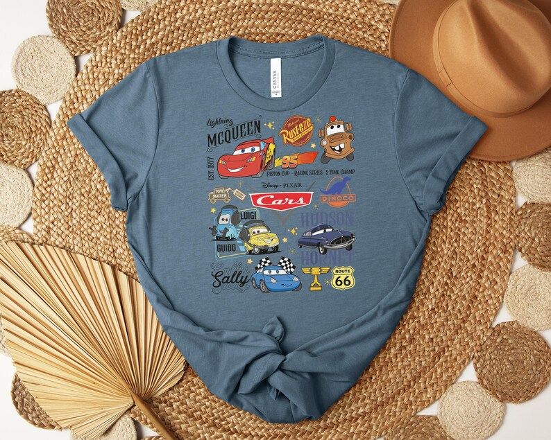Puede incluir: Camiseta azul con personajes de dibujos animados de la pel&iacute;cula Cars, incluyendo a Rayo McQueen, Mate y Sally. El dise&ntilde;o incluye el texto "Lightning McQueen" y "Cars". La camiseta est&aacute; hecha de un material suave.