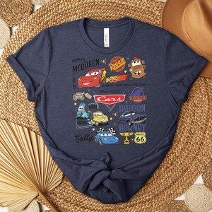 Puede incluir: Camiseta azul marino con un gr&aacute;fico colorido que muestra personajes y logotipos de la pel&iacute;cula Cars de Disney Pixar. El dise&ntilde;o incluye a Rayo McQueen, Mate y otros elementos ic&oacute;nicos. La camiseta es de material suave.