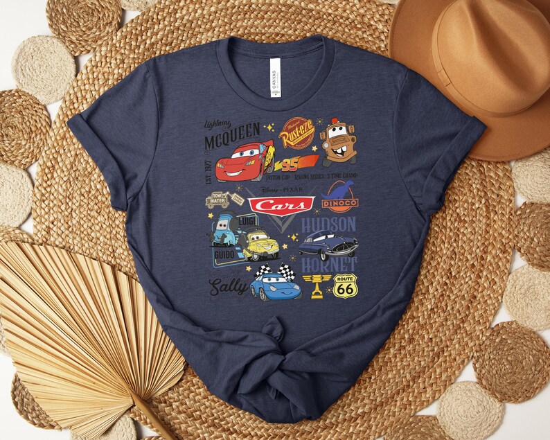 Puede incluir: Camiseta azul marino con un gr&aacute;fico colorido que muestra personajes y logotipos de la pel&iacute;cula Cars de Disney Pixar. El dise&ntilde;o incluye a Rayo McQueen, Mate y otros elementos ic&oacute;nicos. La camiseta es de material suave.