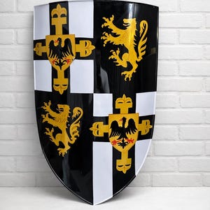 May include: A black and white shield with gold emblems, including lions and crosses, and the word "LEGENDARY" at the bottom. The shield has a glossy finish and is likely a decorative item or prop.