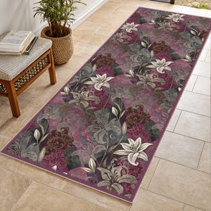 May include: A rectangular runner rug with a floral pattern. The rug features a deep burgundy background with gray, brown, and white lily flower designs. The rug is bordered with a thin burgundy edge.