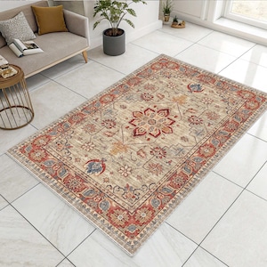 May include: Rectangular area rug with a beige central field and a detailed border. The rug features a central floral medallion in red and orange, surrounded by smaller floral motifs in red, blue, and gray. The border is a darker red with intricate patterns.