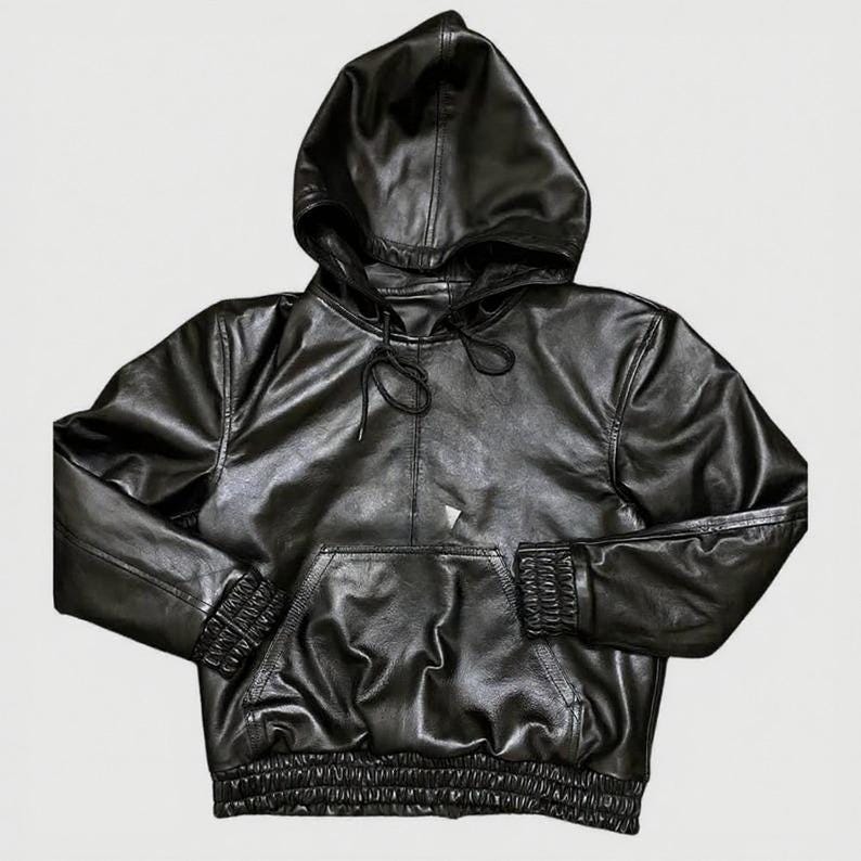 Puede incluir: Sudadera con capucha de cuero negro con capucha con cord&oacute;n, bolsillo tipo canguro y pu&ntilde;os y dobladillo acanalados. La sudadera con capucha es de color negro liso y tiene una textura suave y brillante. Es una prenda de abrigo informal.