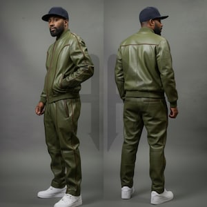 Puede incluir: Chaqueta bomber y pantalón de cuero verde oliva a juego con ribete marrón. La chaqueta tiene cremallera frontal y bolsillos. El pantalón tiene cintura con cordón. El conjunto se combina con una gorra de béisbol negra y zapatillas blancas.