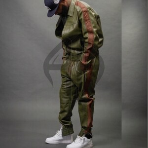 May include: A set of three ceramic mugs with a speckled, cream-colored glaze. Each mug features a different hand-painted design: a blue and green leaf, a yellow flower, and a red berry. The mugs have a simple, rounded shape.