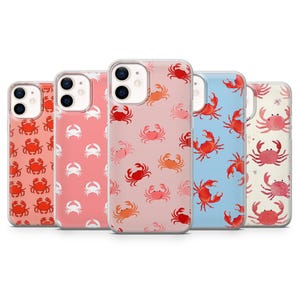 May include: A collection of five phone cases with crab patterns. The cases feature designs in coral, pink, light blue, and cream colors. Each case has a different crab pattern in red, orange, and pink.