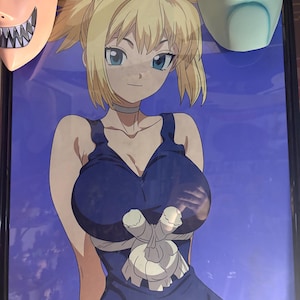 May include: Anime-style illustration of a female character with blonde hair and blue eyes, wearing a blue dress. The artwork is framed and displayed with two masks on either side.