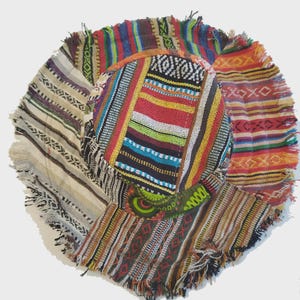 Pode incluir: Um chapéu colorido em estilo patchwork com aba larga. O chapéu apresenta vários tecidos estampados em tons de vermelho, azul, verde, amarelo e castanho. A aba tem uma borda com franjas. O chapéu é de estilo boêmio.