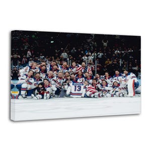 May include: A group of hockey players in white, blue, and red uniforms, posing for a photo on an ice rink. The players are wearing medals and holding an American flag. The jersey of player number 13 is visible.