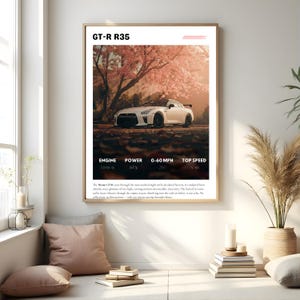 May include: A framed print featuring a white Nissan GT-R R35 sports car parked under a tree with pink blossoms. The print includes specifications: Engine 3.8L V6, Power 565 hp, 0-60 MPH 2.9s, and Top Speed 196 mph.