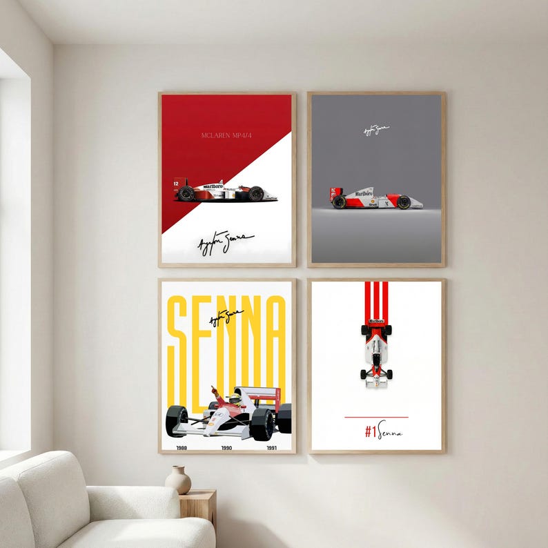 May include: Four framed art prints featuring Formula 1 race cars. Each print has a different design, with a red, white, and black color scheme. One print has the text "SENNA" in yellow. The prints are displayed on a white wall.