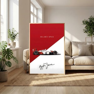 May include: Framed print featuring a McLaren MP4/4 race car in red, white, and black. The print includes the text "McLaren MP4/4" and the signature of Ayrton Senna. The artwork is displayed in a living room setting.