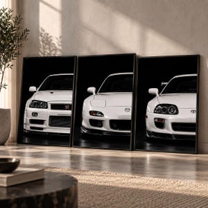 Peut inclure: Un triptyque composé de trois cadres muraux verticaux, chacun présentant la vue avant d'une voiture de sport blanche sur un fond noir uni. Les voitures représentées sont une Nissan GT-R, une Mazda RX-7 et une Toyota Supra, toutes blanches.