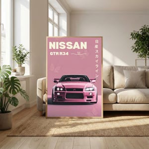 May include: A framed pink poster featuring a pink Nissan GTR R34 car. The poster has the word "NISSAN" at the top, with "GTR R34" below it. Japanese text is on the right side of the poster. The poster is displayed in a living room.