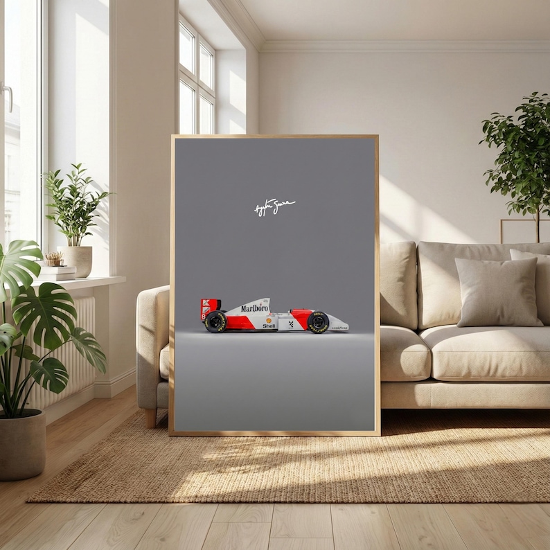 May include: Framed print featuring a Formula 1 race car in red, white, and black, with the Marlboro logo. The car is set against a gray background, with the signature of Ayrton Senna. The print is displayed in a room with natural light.