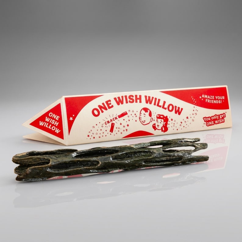 Puede incluir: Una pieza cil&iacute;ndrica, porosa y de color marr&oacute;n oscuro de madera de cholla colocada frente a una caja de cart&oacute;n triangular. La caja es de color crema y rojo con el texto "ONE WISH WILLOW", "AMAZE YOUR FRIENDS!" y "You only get ONE WISH".