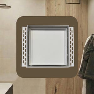 May include: A white square shower drain with a metal frame and a brown background. The drain is set against a backdrop of light-colored tile and wood paneling, suggesting a modern bathroom design.