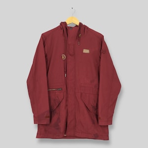May include: A burgundy hooded jacket with a drawstring closure and multiple pockets. The jacket features a small patch on the upper chest and is hanging on a wooden hanger. The jacket has a zipper closure and a button closure.