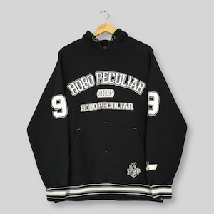 May include: Black hoodie with the text "HOBO PECULIAR" in white arched lettering. The number "9" is on each sleeve. The hoodie has a front pocket and a white and black striped bottom hem.