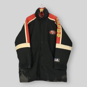 Może przedstawiać: Czarno-czerwono-kremowa kurtka puchowa z logo San Francisco 49ers na piersi, napisem 49ers złotymi literami na lewym rękawie oraz naszywką NFL Starter na lewym mankiecie, zapinana z przodu na zatrzaski.