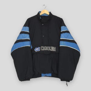 May include: Black and blue Carolina jacket with a high collar and a front pocket. The sleeves feature blue stripes with white accents. The word "CAROLINA" is embroidered on the front.