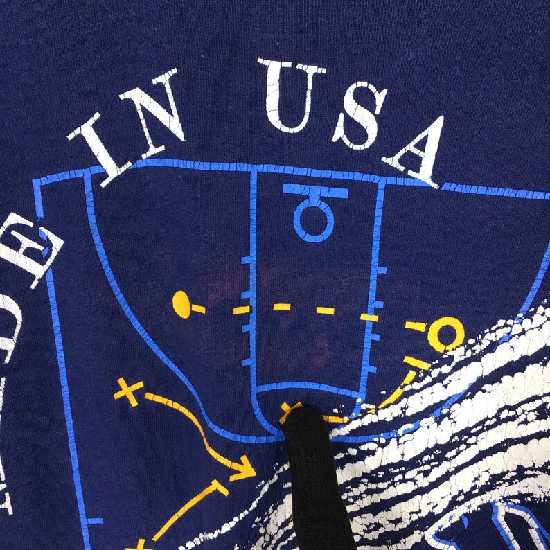 May include: Navy blue t-shirt with a basketball court graphic. The words "IN USA" are printed in white. The graphic includes a basketball court design with yellow and white accents.