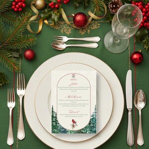 Peut inclure: Une table de No&euml;l festive avec une nappe verte, des assiettes blanches &agrave; bordure dor&eacute;e, des couverts et un menu. Les d&eacute;corations comprennent des boules rouges, du houx, des branches de pin et une bougie allum&eacute;e.
