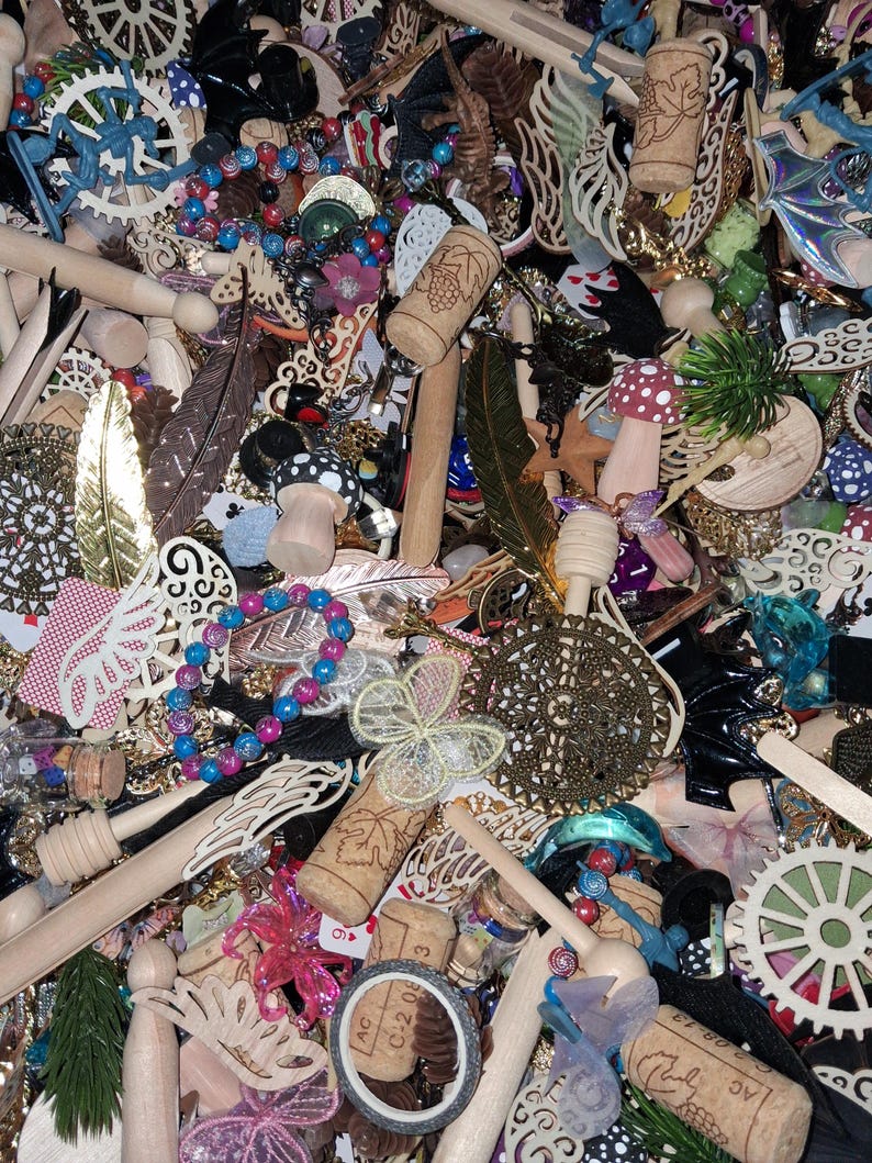 May include: A collection of various craft supplies and decorative elements. The image includes wooden dowels, corks, beads, feathers, and decorative cutouts. There are also small mushroom figurines, floral accents, and a variety of other embellishments in a mix of colors and textures.