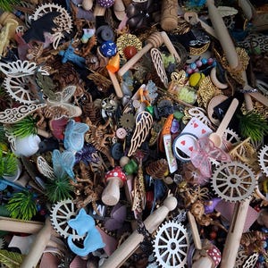 May include: A collection of assorted craft supplies, including wooden gears, miniature mushrooms, playing cards, and decorative wings. The items are in various colors, including red, blue, gold, and white. The image is a close-up shot of the items.
