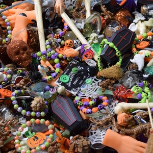 Doll hands, skull bracelets, coffins, wooden buttons, eyeballs. charms, obsidian chips, green aventurine chips, skulls, bones, witches brew spoons, and mini brooms litter the page.