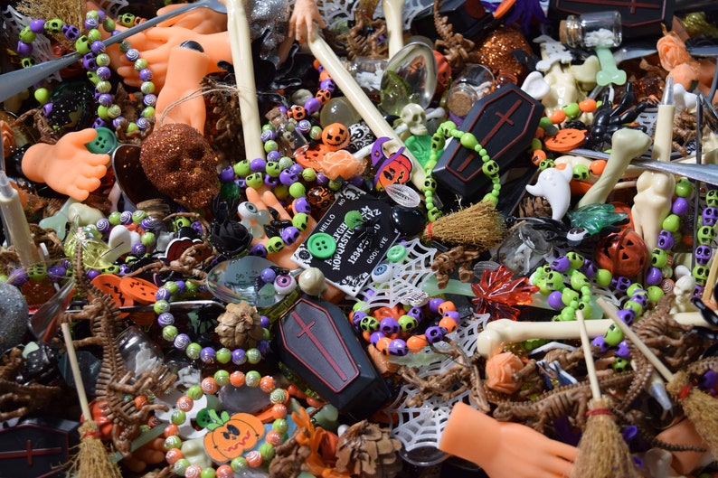 Doll hands, skull bracelets, coffins, wooden buttons, eyeballs. charms, obsidian chips, green aventurine chips, skulls, bones, witches brew spoons, and mini brooms litter the page.