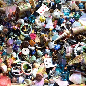 May include: A collection of small, colorful objects including dice, playing cards, buttons, beads, and corks. The items are scattered, creating a visually rich and textured display. Various shapes and sizes are present, with a mix of natural and manufactured materials.