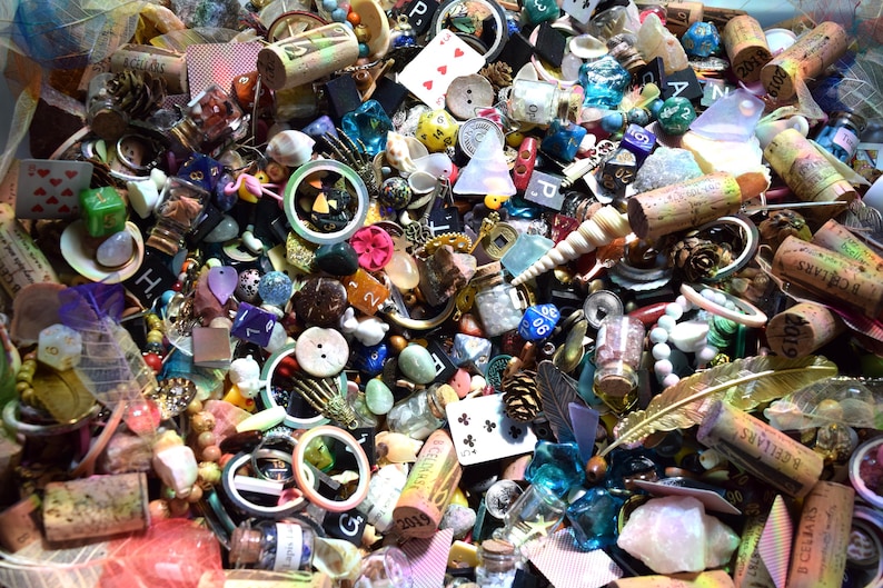 May include: A collection of small, colorful objects including dice, playing cards, buttons, beads, and corks. The items are scattered, creating a visually rich and textured display. Various shapes and sizes are present, with a mix of natural and manufactured materials.