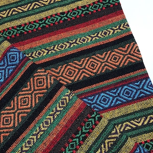 May include: Multicolored fabric with a geometric pattern. The fabric is woven with stripes of red, orange, yellow, green, blue, and black. The pattern is made up of repeating geometric shapes, including squares, triangles, and diamonds.